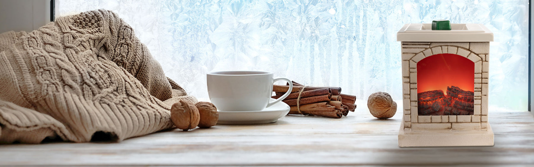 Fireplace wax warmer, sweater and cup of tea on a table